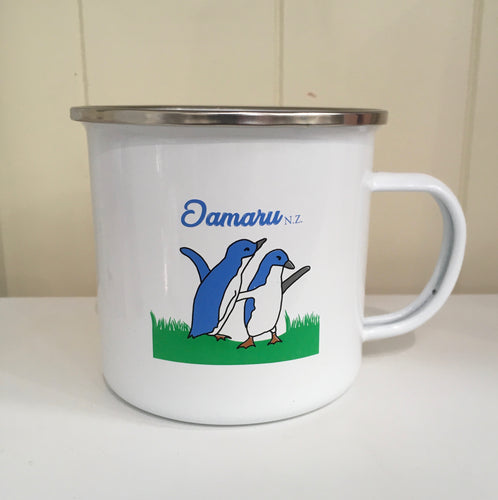 white enamel mug with penguins and Oamaru NZ printed on it