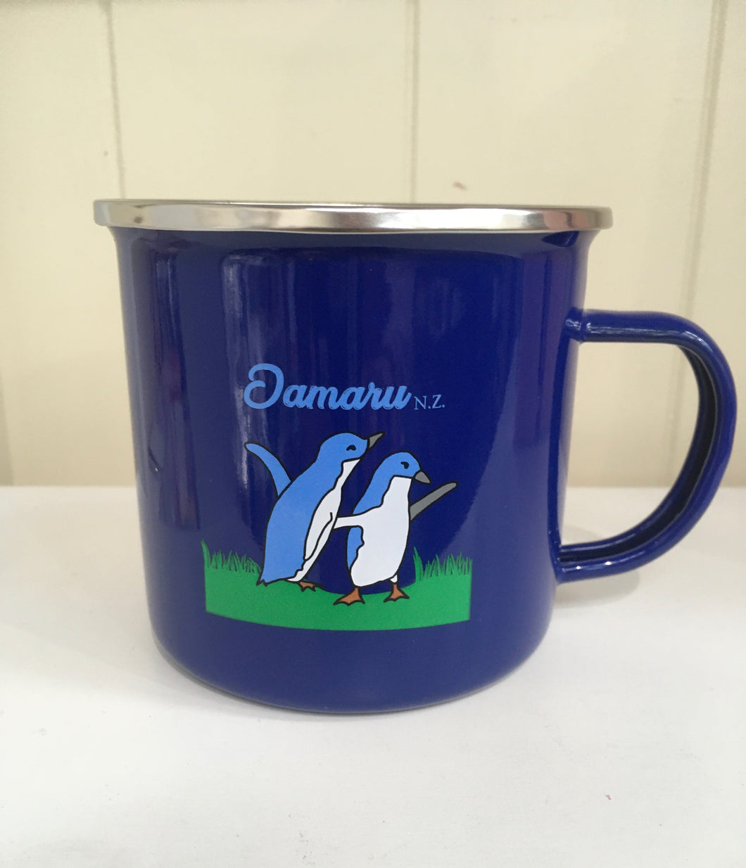 blue enamel mug with penguins and Oamaru nz printed on it